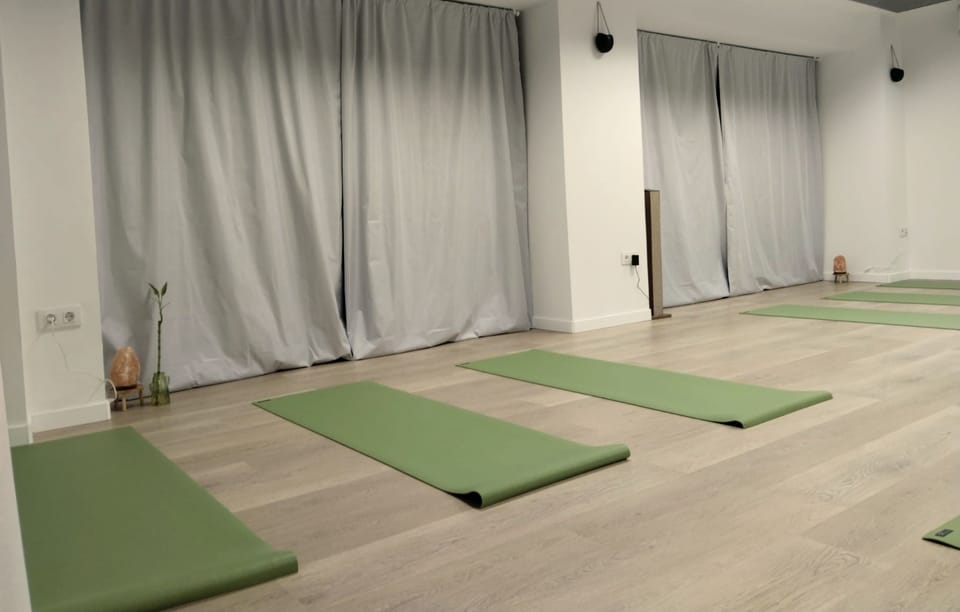 La sala del centro con esterillas verdes extendidas sobre el suelo de madera y una lámpara de sal junto a la pared.